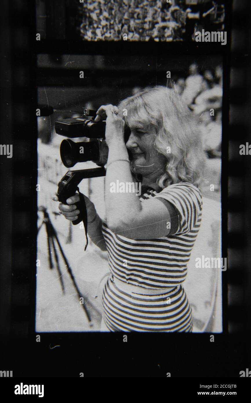Belle photographie en noir et blanc vintage des années 1970 d'une femme cinéaste prenant une photo avec son appareil photo. Banque D'Images