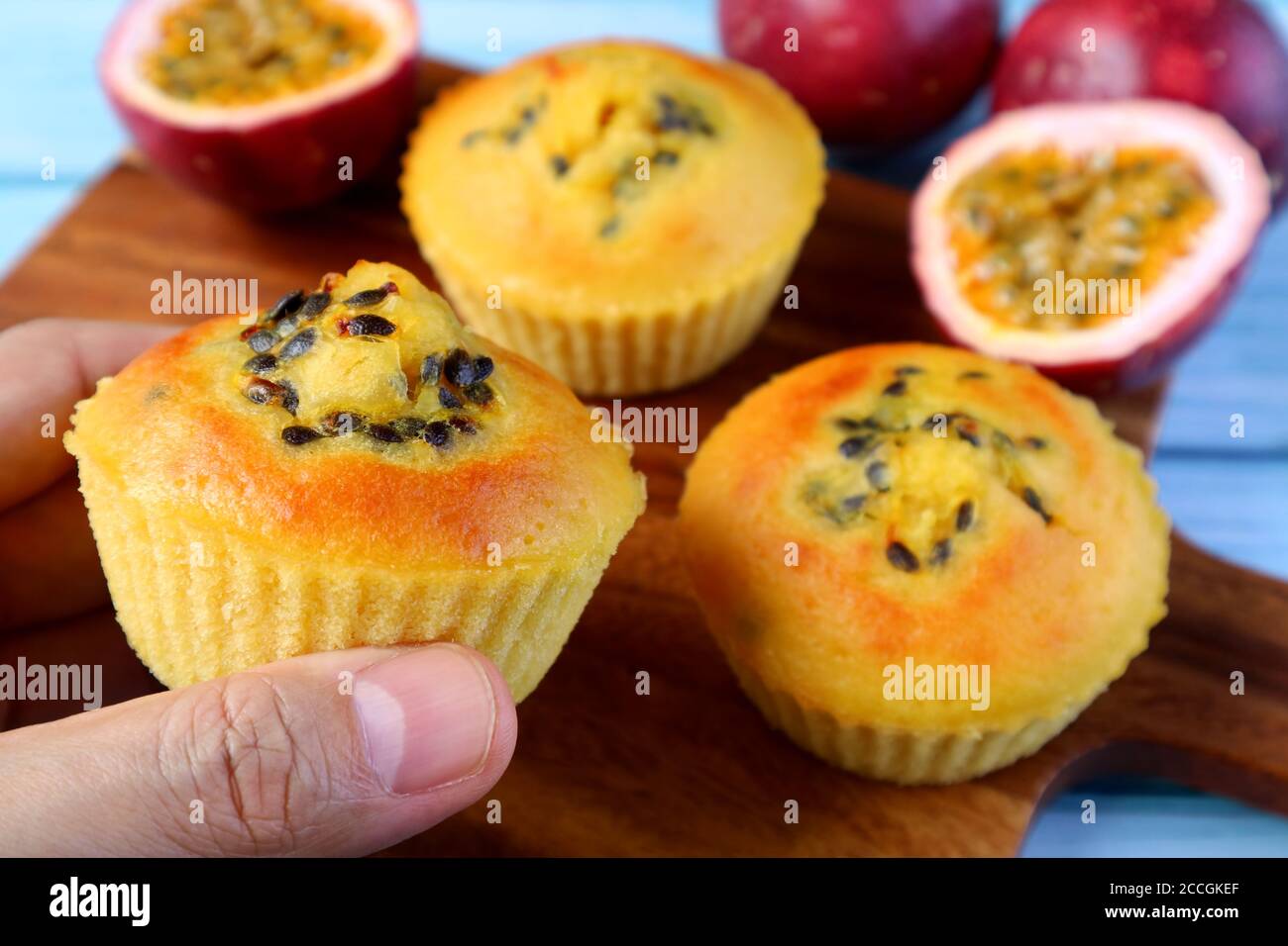 Gros plan main tenant un muffin aux fruits de la passion avec un cupcake flou Et fruits frais en arrière-plan Banque D'Images