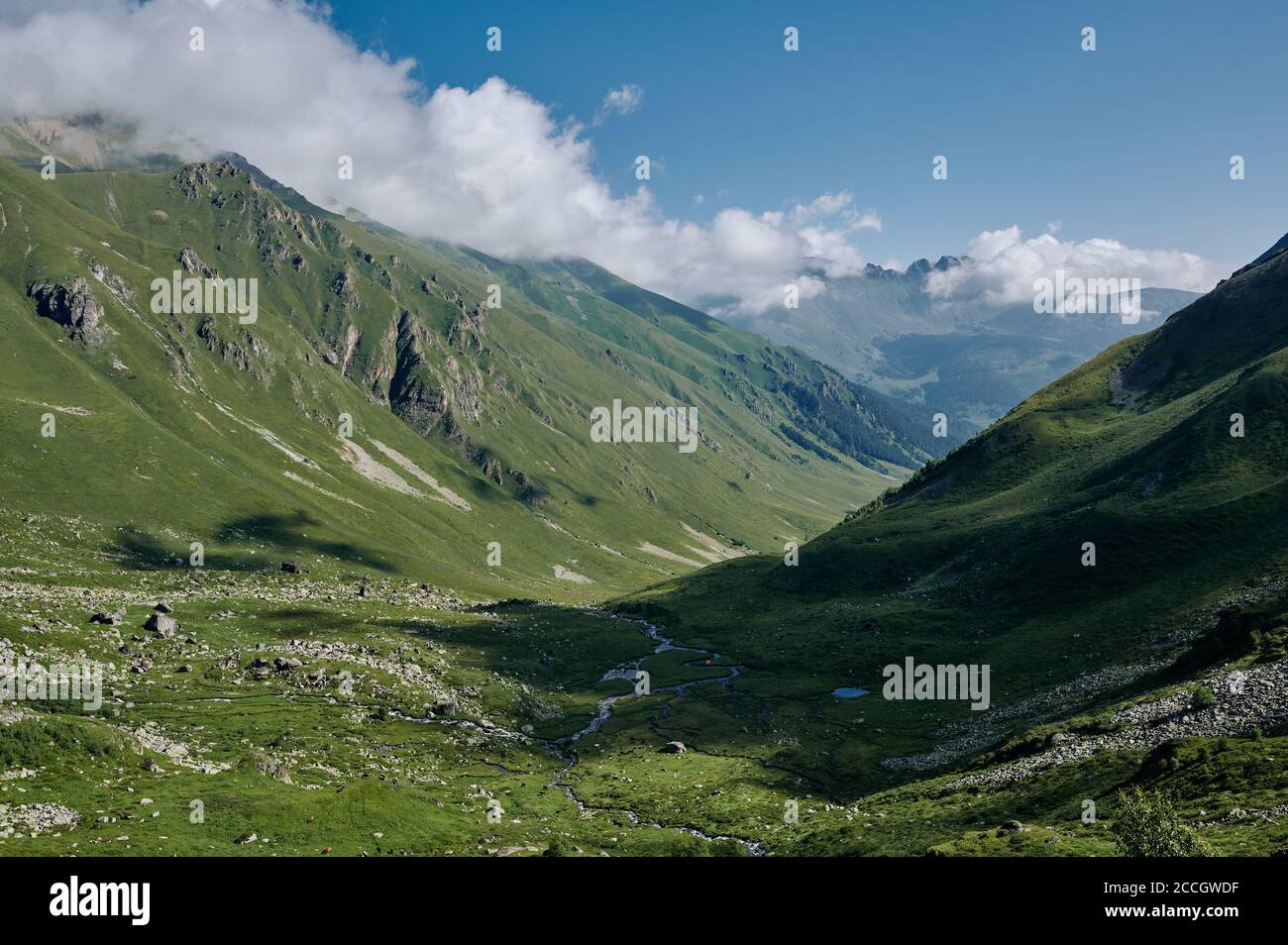 Majestueux paysage d'été de vallée de montagne avec collines vertes, rivière et nuages blancs. Seule petite tente orange parmi la nature sauvage Banque D'Images