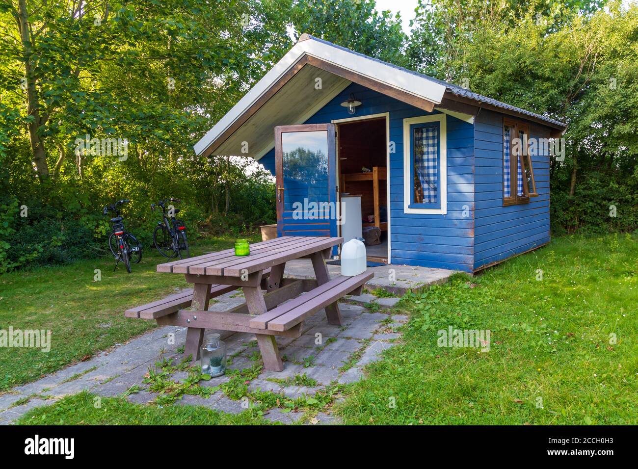Petite maison d'été confortable en bois bleu entre fleurs et arbres Banque D'Images