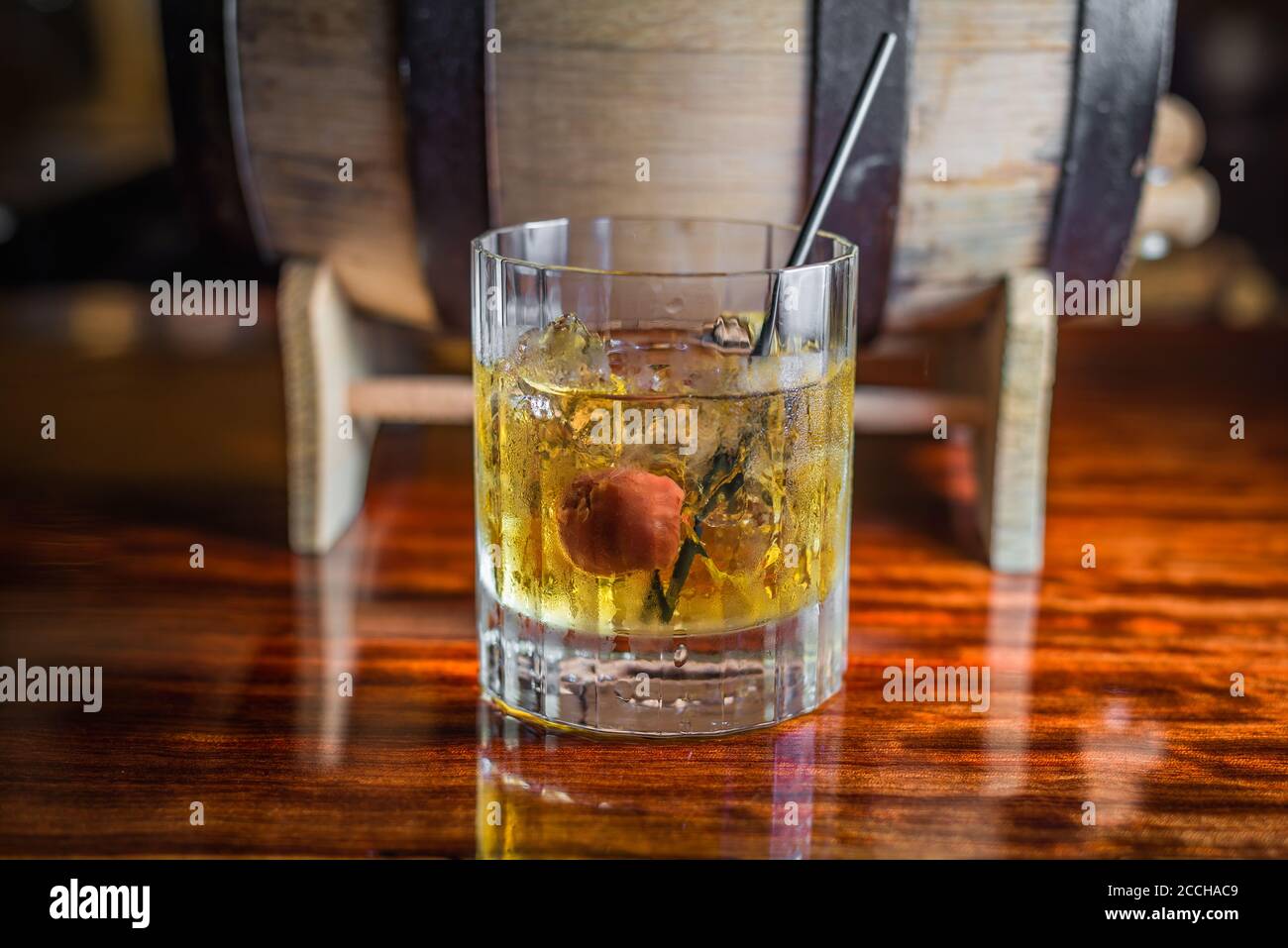 Un cocktail artisanal classique à base de whisky bourbon se trouve devant un tonneau sur un bar en bois. Banque D'Images