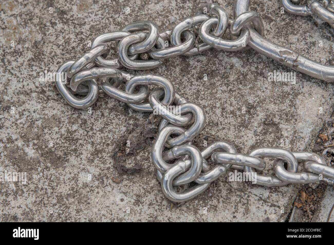 Chaîne industrielle. Chaîne métallique brillante sur béton. Pour la chaîne d'approvisionnement, les maillons forts, le maillon faible, enchaîné au travail, l'esclavage moderne, confinement COVID au Royaume-Uni Banque D'Images
