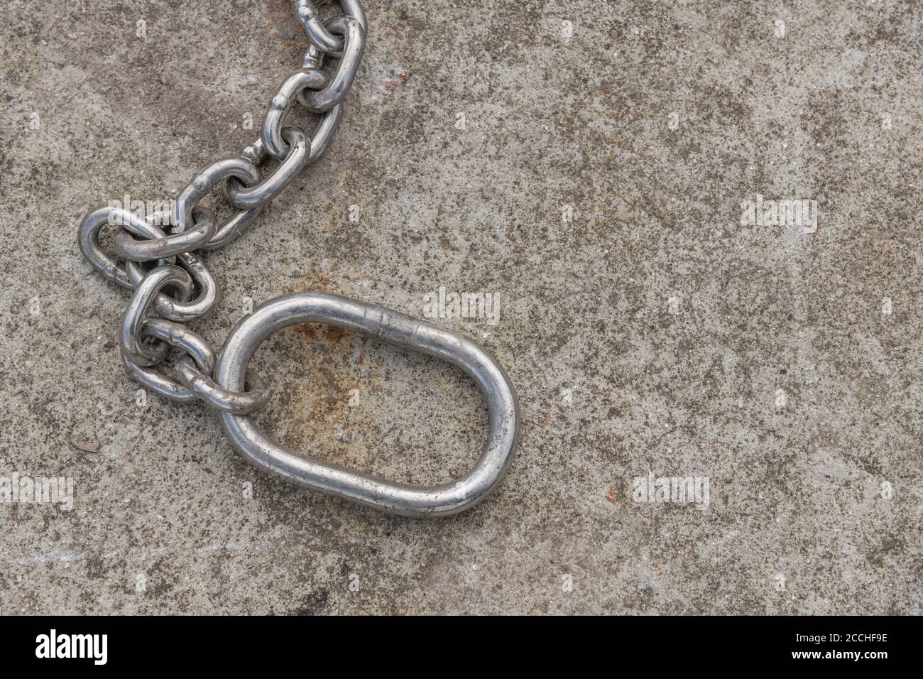 Chaîne industrielle. Chaîne métallique brillante sur béton. Pour la chaîne d'approvisionnement, les maillons forts, le maillon faible, enchaîné au travail, l'esclavage moderne, confinement COVID au Royaume-Uni Banque D'Images