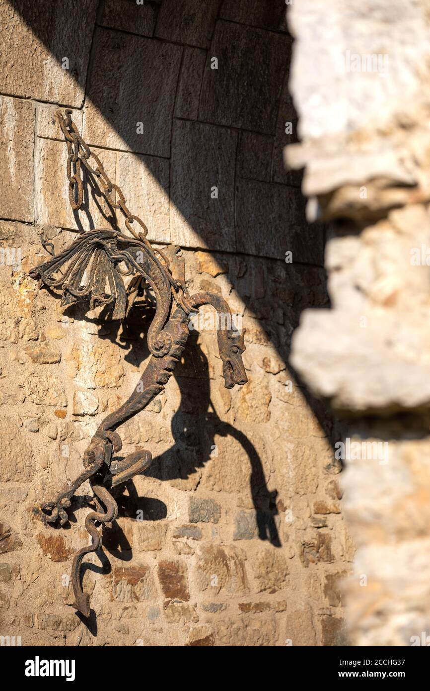 Gros plan d'un dragon de fer forgé suspendu au Mur d'un ancien château slovène en fin d'après-midi léger Banque D'Images