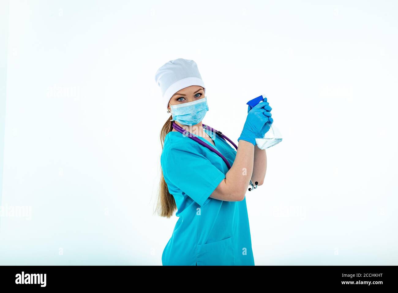 Une femme médecin ou infirmière en uniforme utilise un spray désinfectant. Désinfection. Protection contre les virus et les bactéries. Isolé sur un fond blanc Banque D'Images