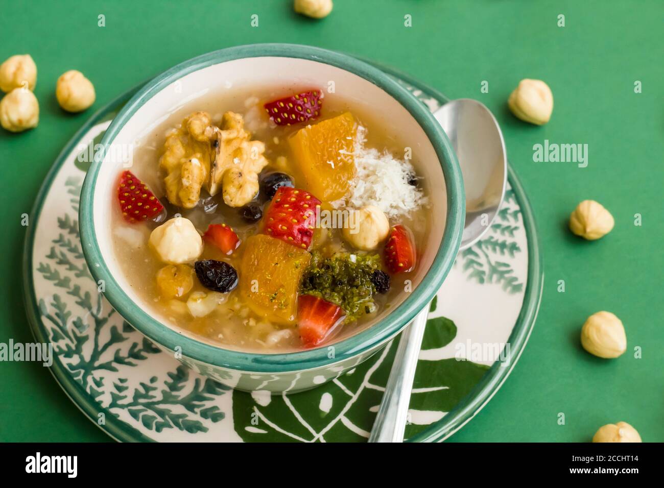 Dessert turc traditionnel Ashura ou Noah's Pudding dans des bols verts élégants sur fond vert avec des noisettes. Banque D'Images