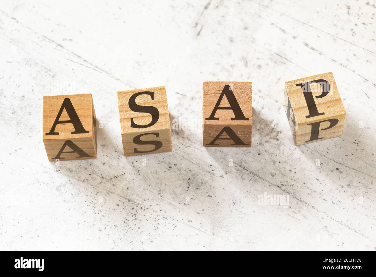 Quatre cubes en bois avec les lettres ASAP (signifiant Dès que possible) sur le tableau de travail blanc. Banque D'Images