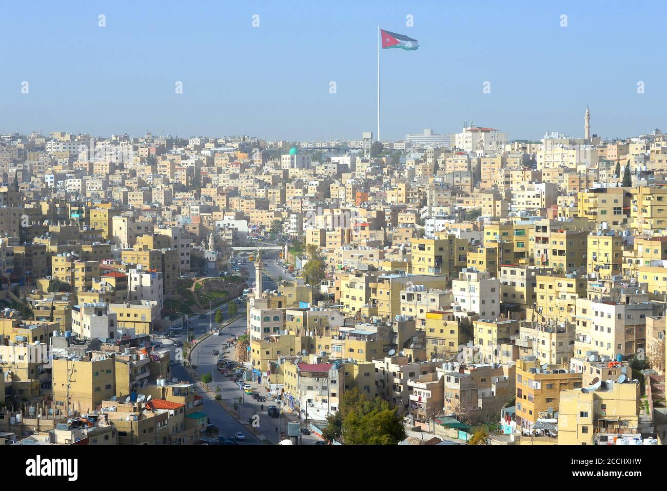 Amman, horizon de Jordanie vu du sommet de la Citadelle. Ville aux constructions jaunes et avenue Al Hashemi Street. Drapeau jordanien agité. Banque D'Images