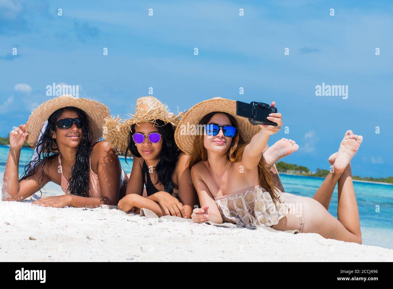 Trois filles heureux amis en vêtements d'été prenant un selfie À la plage de Los Roques Venezuela Banque D'Images