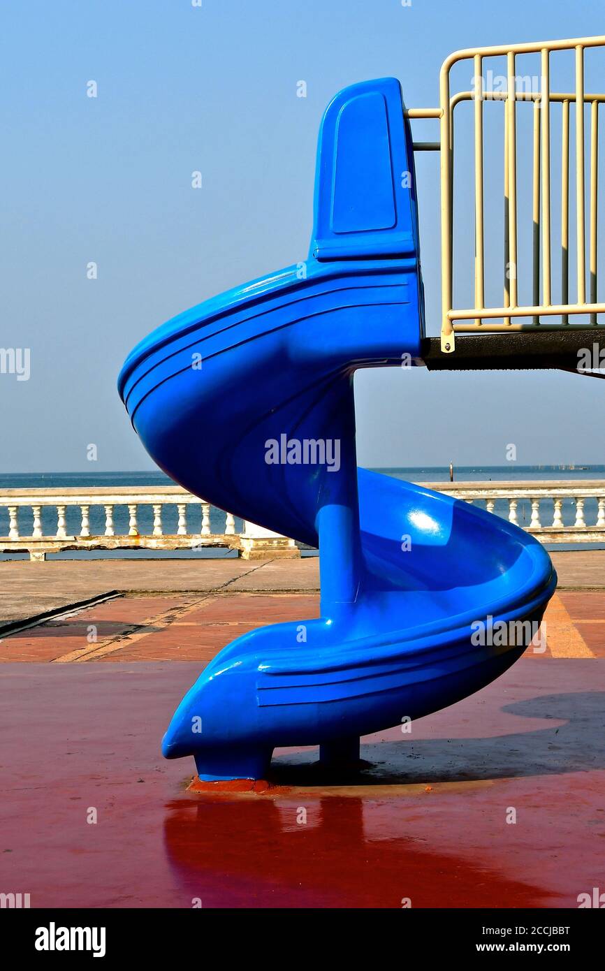 Glissoire bleu vif dans un parc de jeux d'aventure pour enfants en plein air, au bord de la mer, avec un ciel bleu vif. Banque D'Images