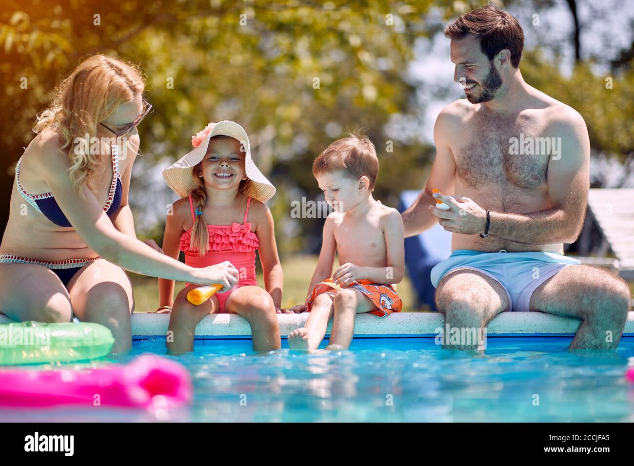 Protection solaire - la famille met crème solaire sur les petits enfants souriants avant de nager. Banque D'Images