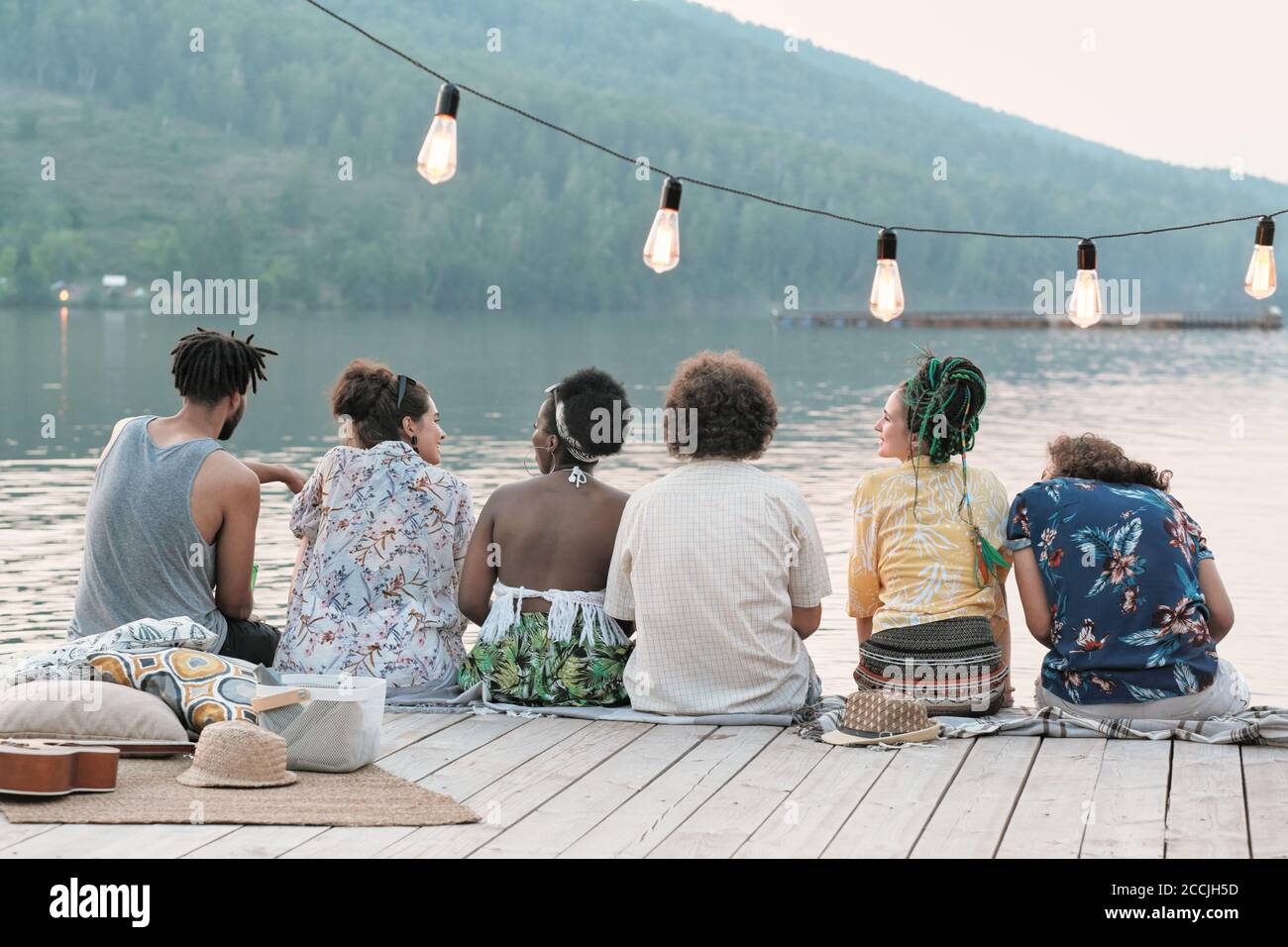 Vue arrière d'un groupe d'amis assis sur un quai et parler entre eux ils appréciant la nature Banque D'Images