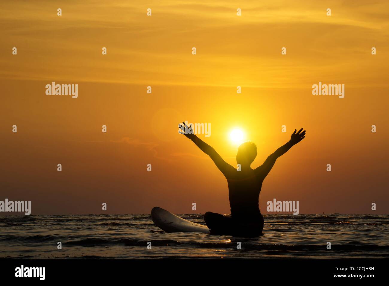 Silhouette d'homme de surf assis sur une planche de surf, bras ouverts. Surf sur la plage au coucher du soleil. Sports nautiques en plein air aventure style de vie.activité d'été. Une Asie magnifique Banque D'Images