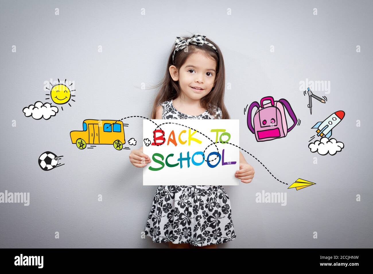 Concept de retour à l'école: Gaie souriante petite fille tenir le papier écrire à l'école avec coloré avec le dessin animé autour. Mignonne mixte race fille moitié thaï Banque D'Images