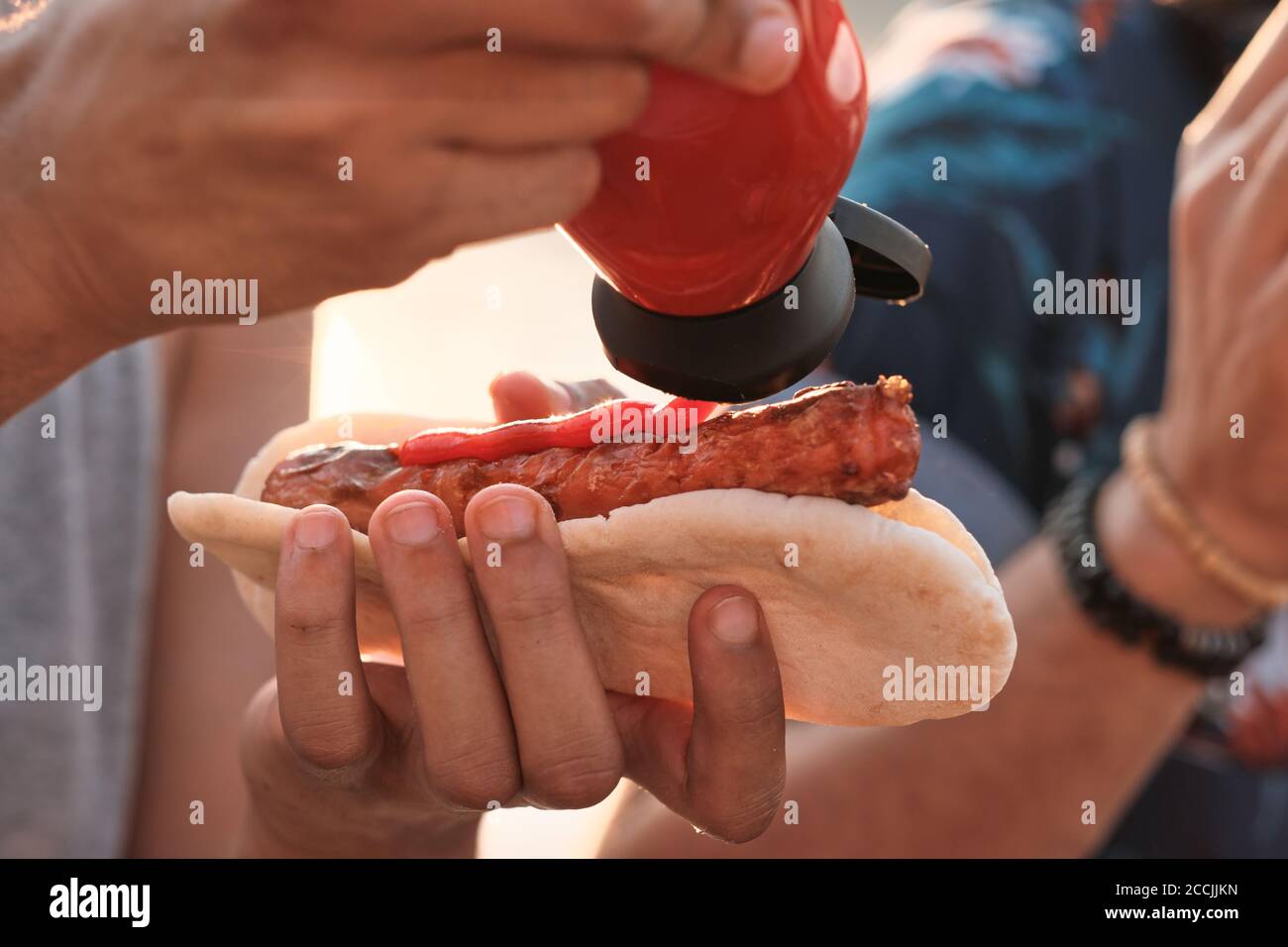 Gros plan sur l'homme mangeant des hot-dogs avec ketchup au pique-nique à l'extérieur Banque D'Images