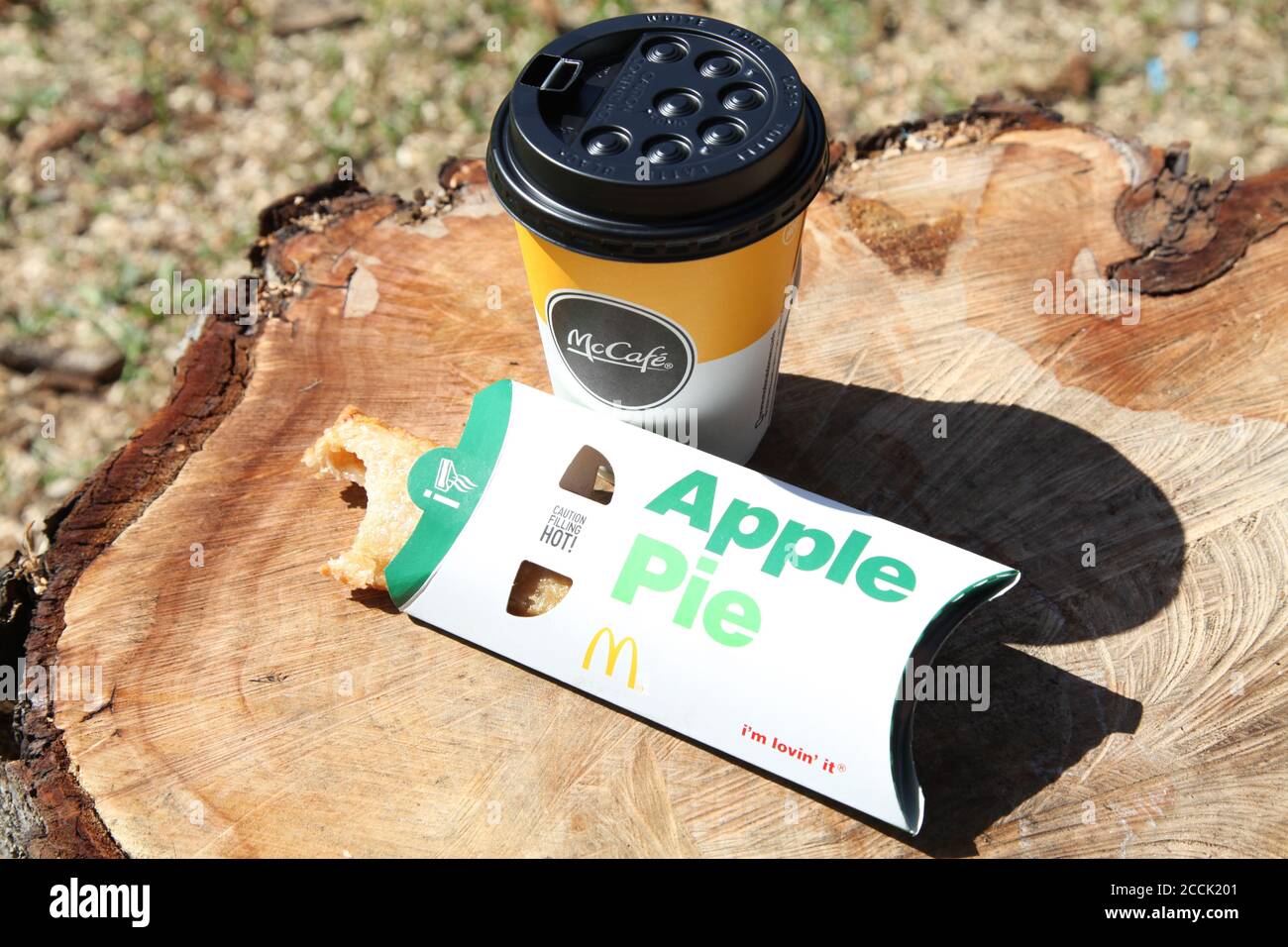 Tarte aux pommes McDonald's (mordu) et tasse de café McCafe à l'extérieur, jour ensoleillé, 2020 Banque D'Images