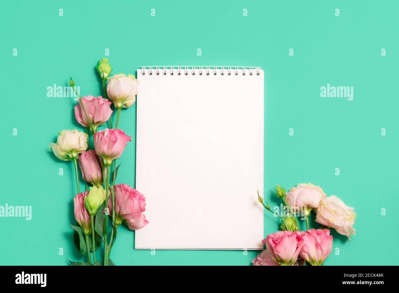 Carnet vierge avec fleurs roses sur fond vert, maquette Banque D'Images