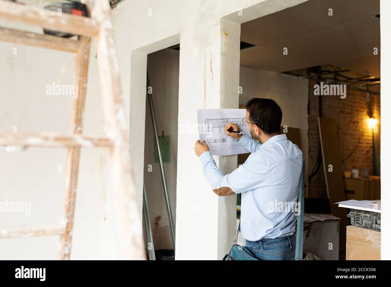 Architecte travaillant sur un plan dans une maison en construction Banque D'Images
