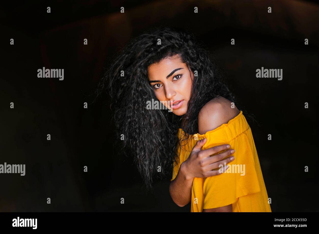 Portrait d'une jeune femme aux cheveux noirs, fond sombre Banque D'Images