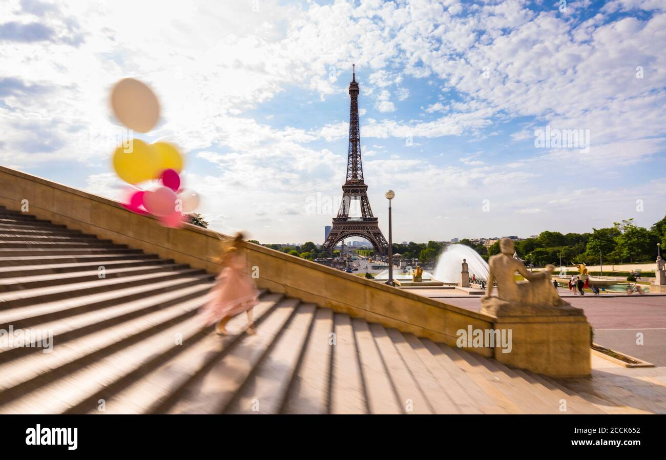 Femme avec des ballons grimpant en escalier contre la Tour Eiffel à Paris, France Banque D'Images