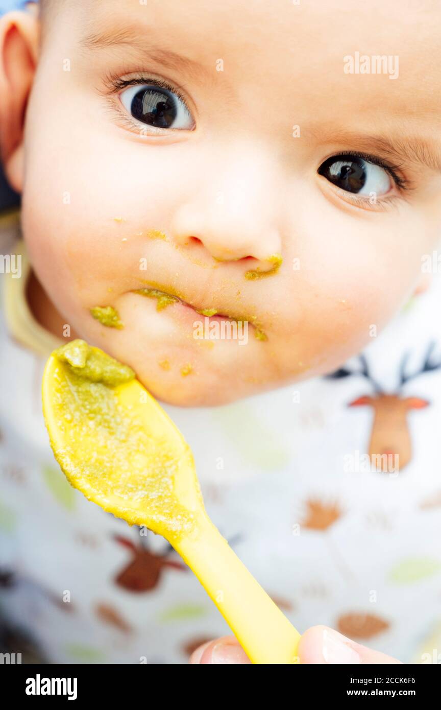 Portrait de bébé garçon mangeant, père tenant la cuillère Banque D'Images