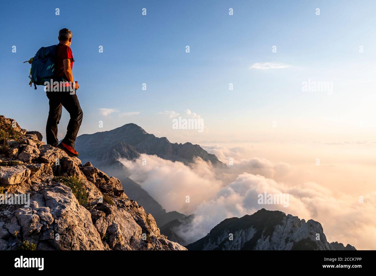 Homme admirant la vue tout en se tenant sur le sommet de la montagne aux Alpes de Bergamasque, Italie Banque D'Images