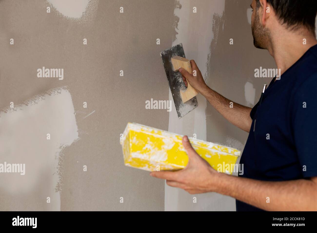 Un ouvrier de construction plâtrage mur dans une maison Banque D'Images