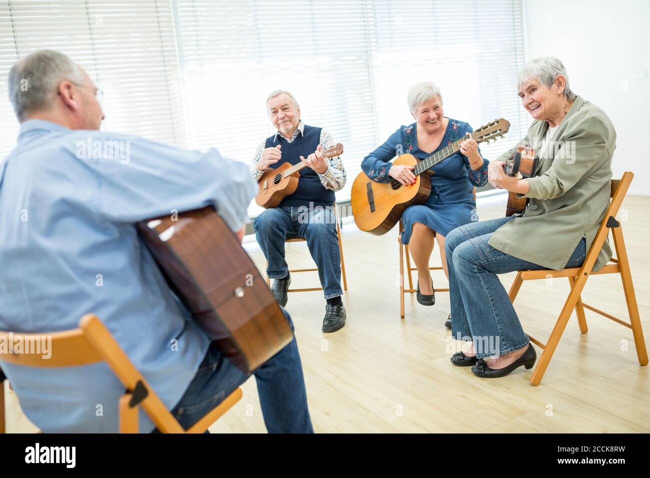 Aînés à la maison de retraite assistant à la classe de guitare, faisant de la musique Banque D'Images