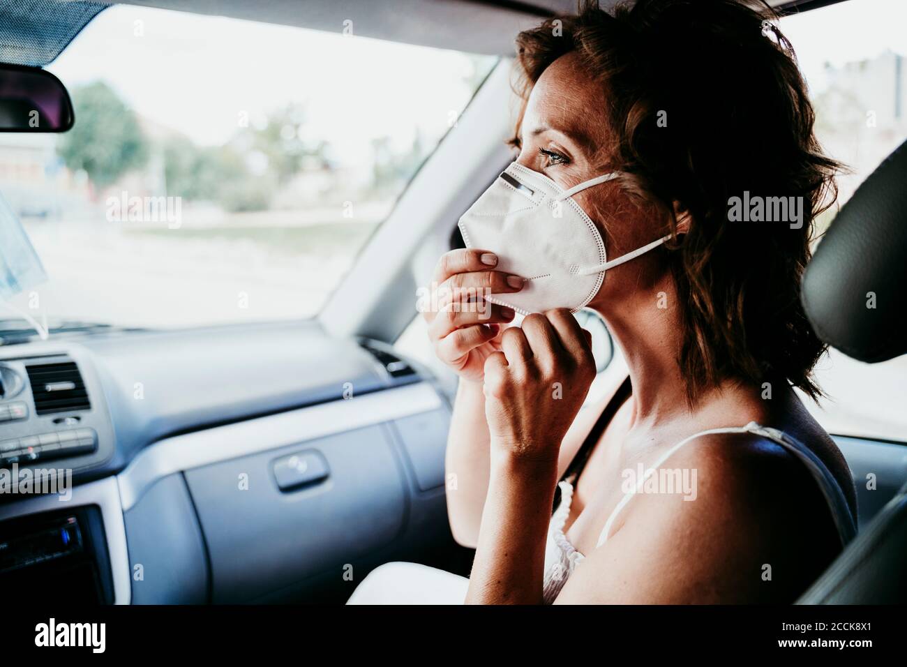 Femme portant un masque de protection dans la voiture pendant COVID-19 Banque D'Images