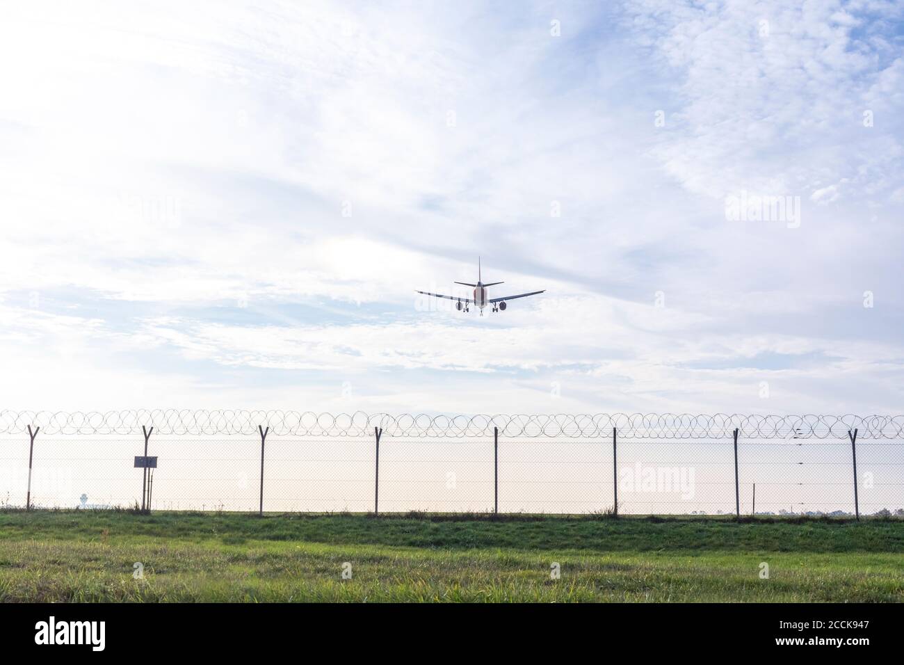 L'avion se prépare à atterrir au-dessus d'une clôture métallique Banque D'Images