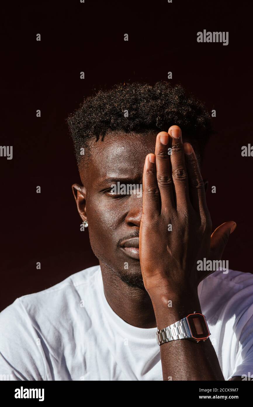 Gros plan du jeune homme africain couvrant le visage avec la main Banque D'Images