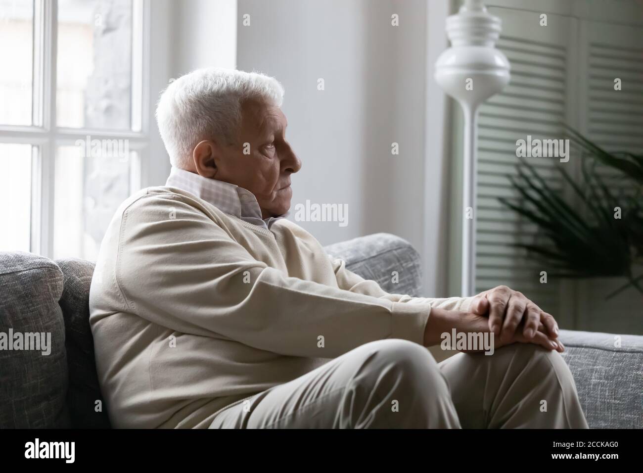 Stressé malheureux vieux retraité homme assis seul sur le canapé. Banque D'Images
