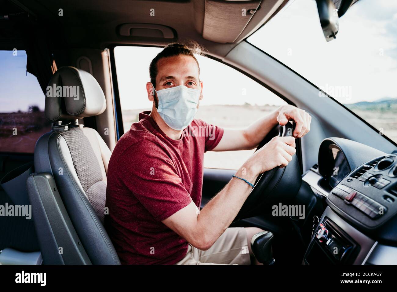 Homme portant un masque de visage assis en voiture pendant COVID-19 Banque D'Images