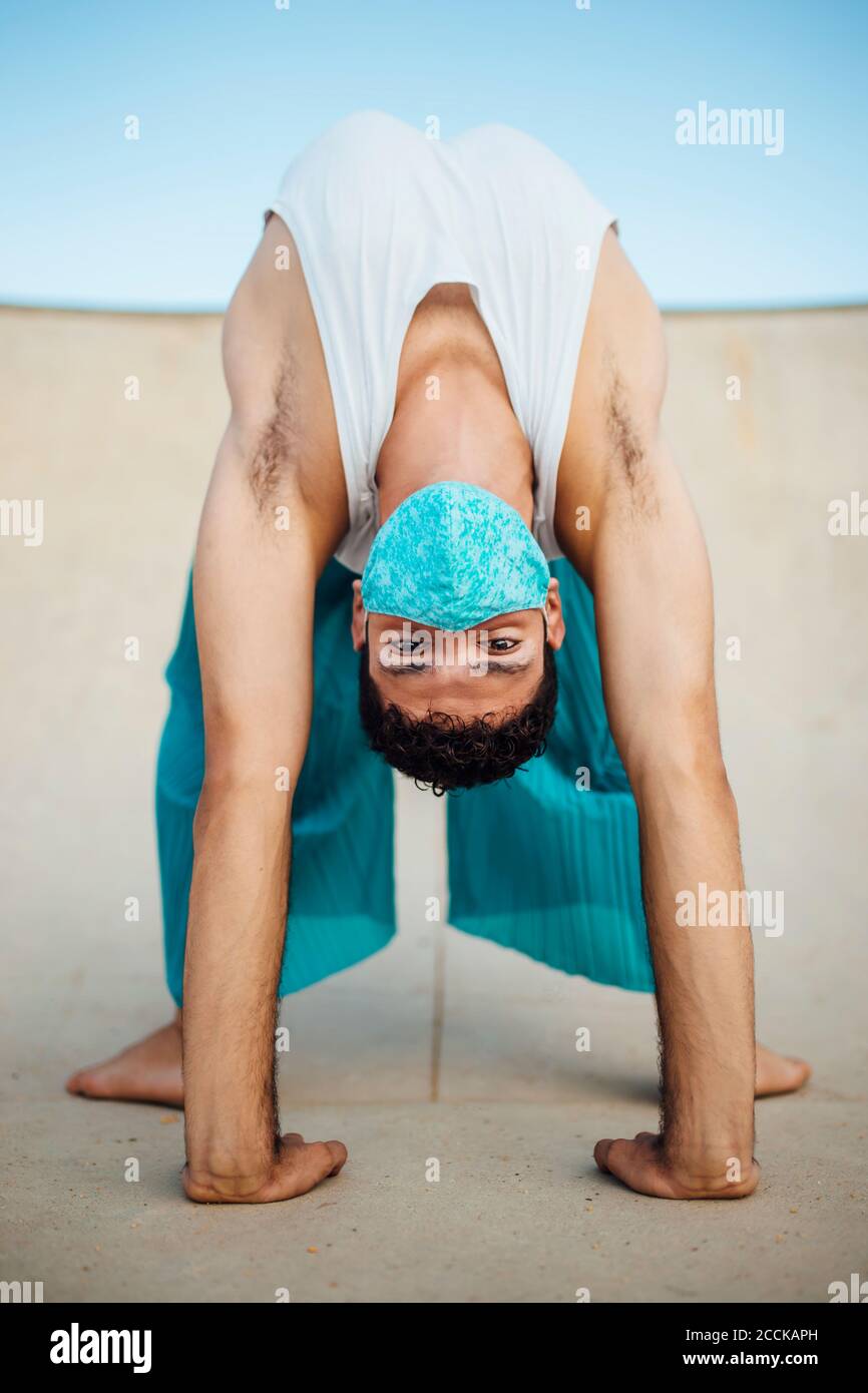 Jeune homme portant un masque pratiquant la pose de roue sur une rampe de sport Banque D'Images