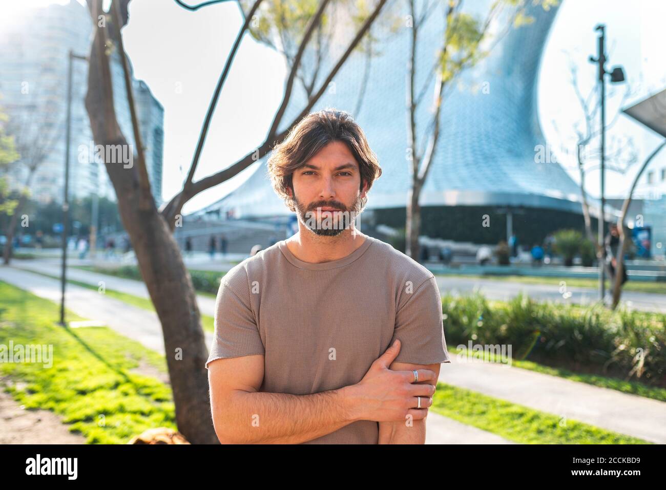 Homme barbu debout dans la rue contre un bâtiment moderne pendant les trajets en ville Banque D'Images
