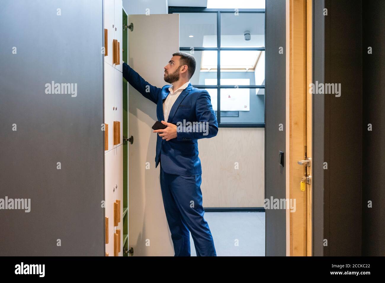 Homme d'affaires barbu cherchant quelque chose dans le vestiaire Banque D'Images