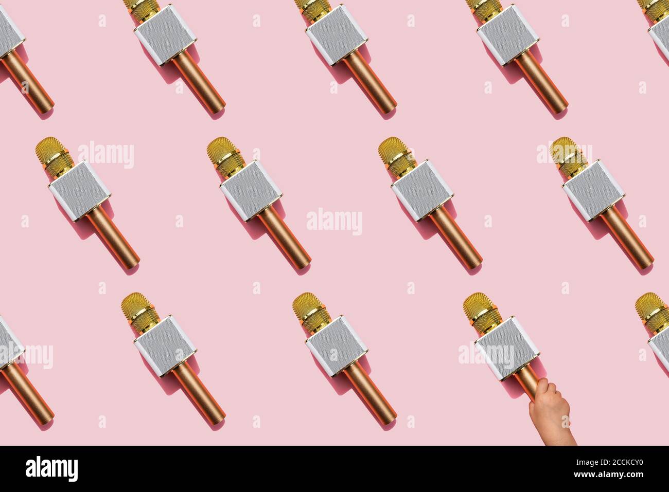 Motif de microphones dorés sur fond rose avec la main bébé fille en ramasser un Banque D'Images