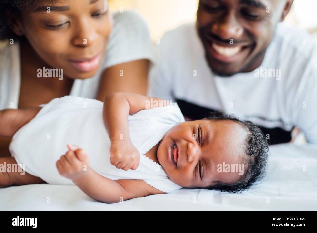 Gros plan de parents souriants regardant la fille du nouveau-né dormir lit Banque D'Images