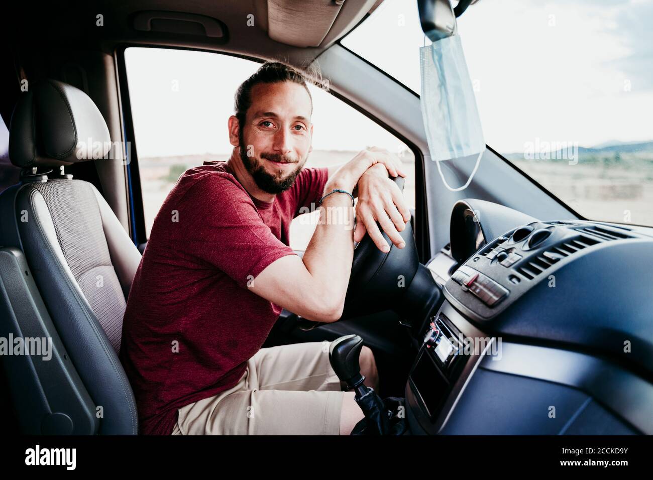 Homme souriant assis en voiture pendant la COVID-19 Banque D'Images