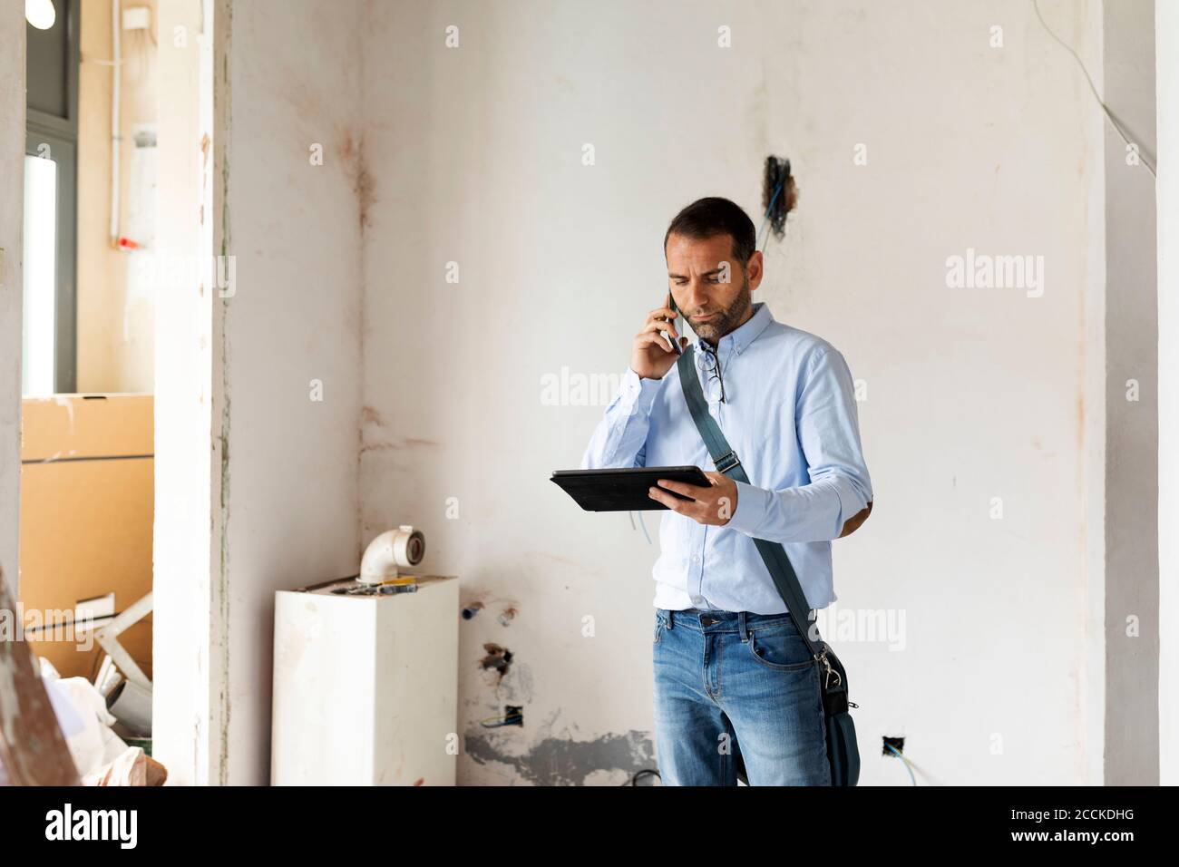 Architecte avec tablette sur le téléphone dans une maison en dessous construction Banque D'Images