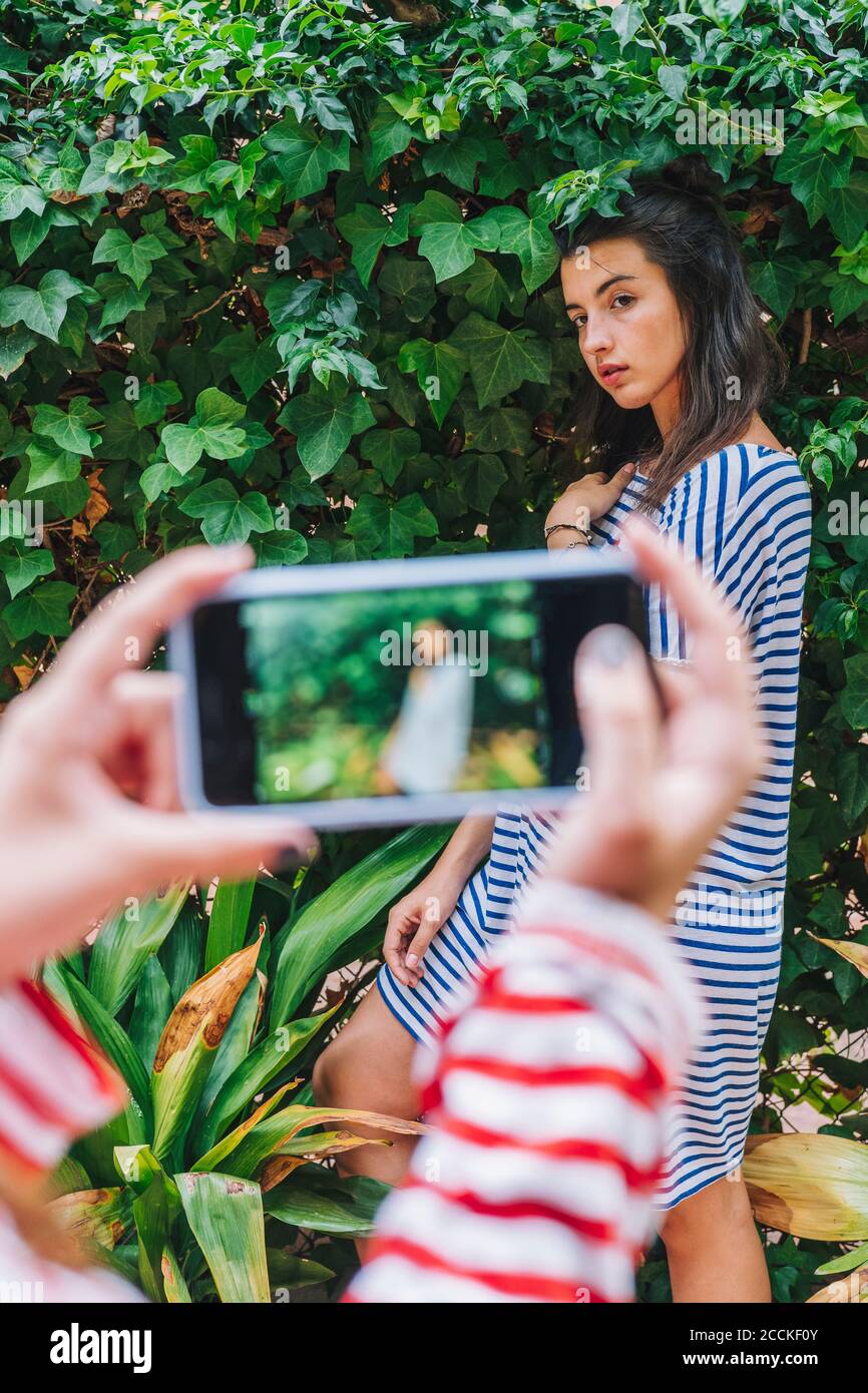 Une fille qui photographie sa sœur à l'aide d'un smartphone Banque D'Images