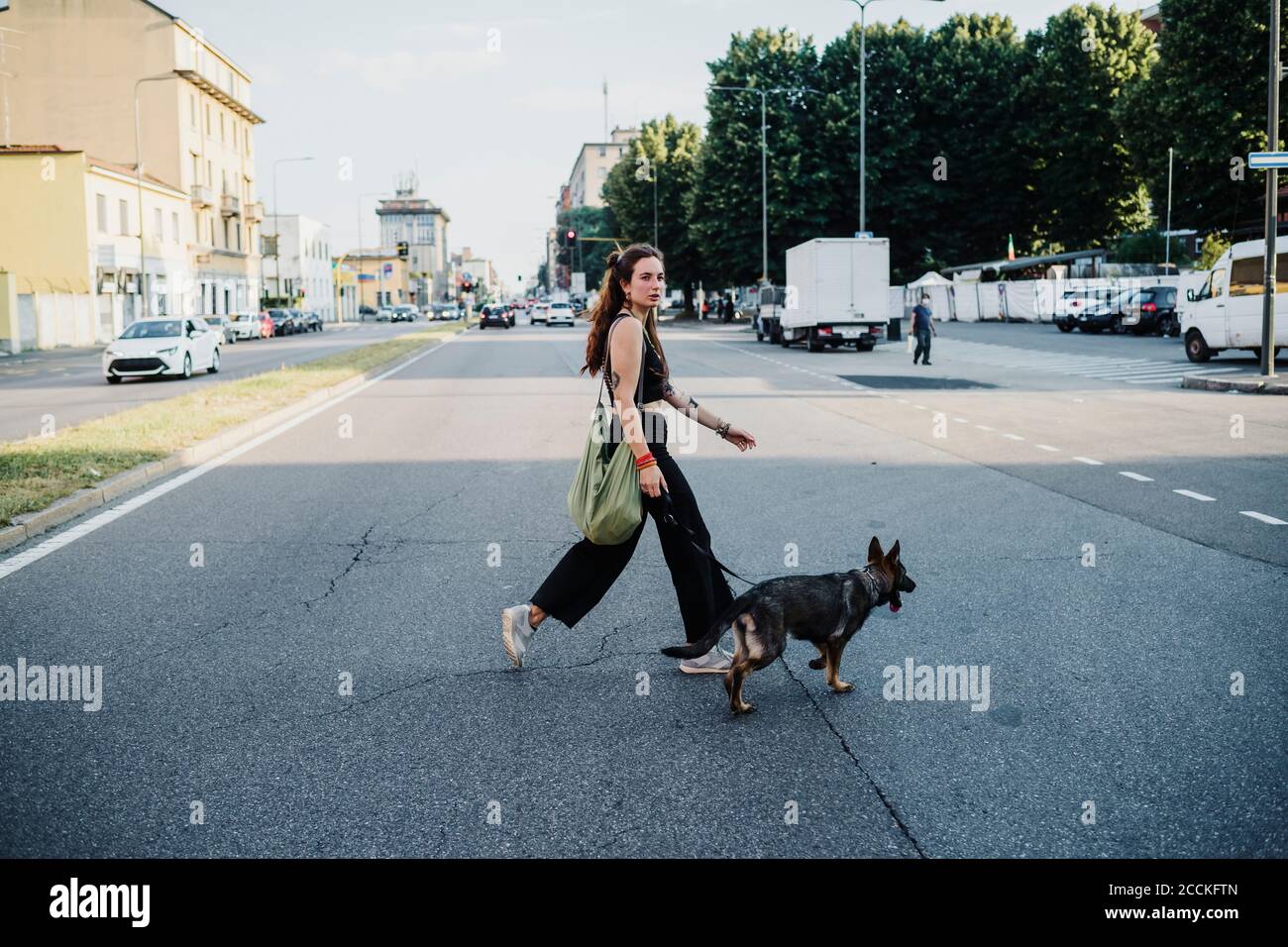 Femme traversant la route avec un chien en ville Banque D'Images