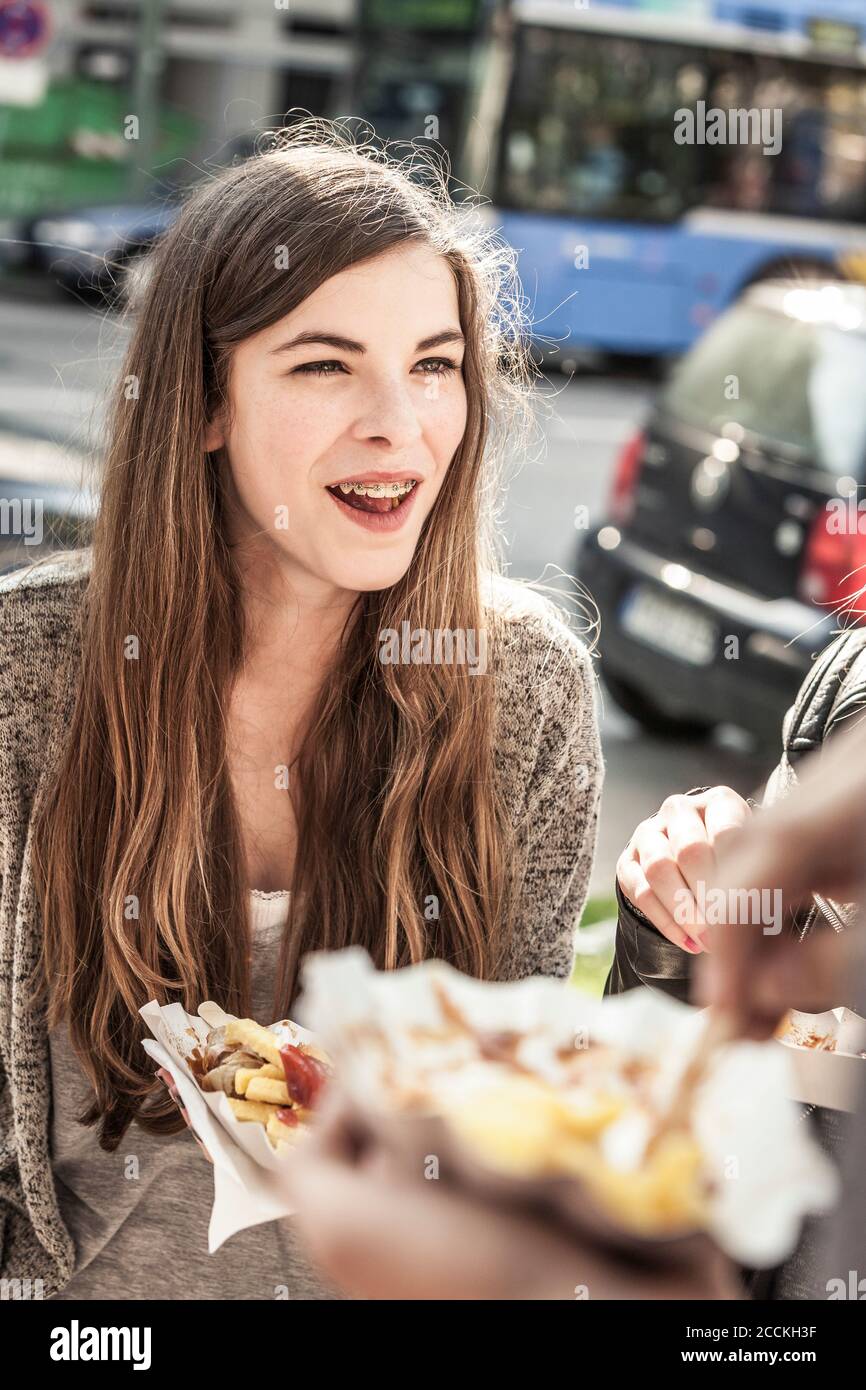 Portrait d'une adolescente en compagnie d'amis la ville ayant un snack Banque D'Images