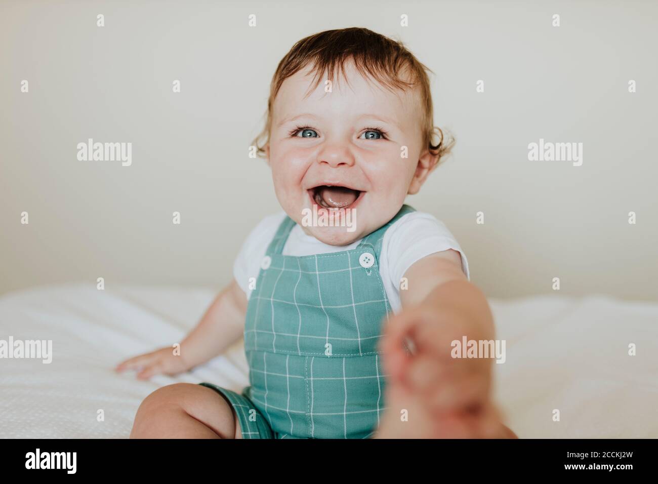 Gros plan de la petite fille qui rit tout en s'asseyant sur le lit à accueil Banque D'Images