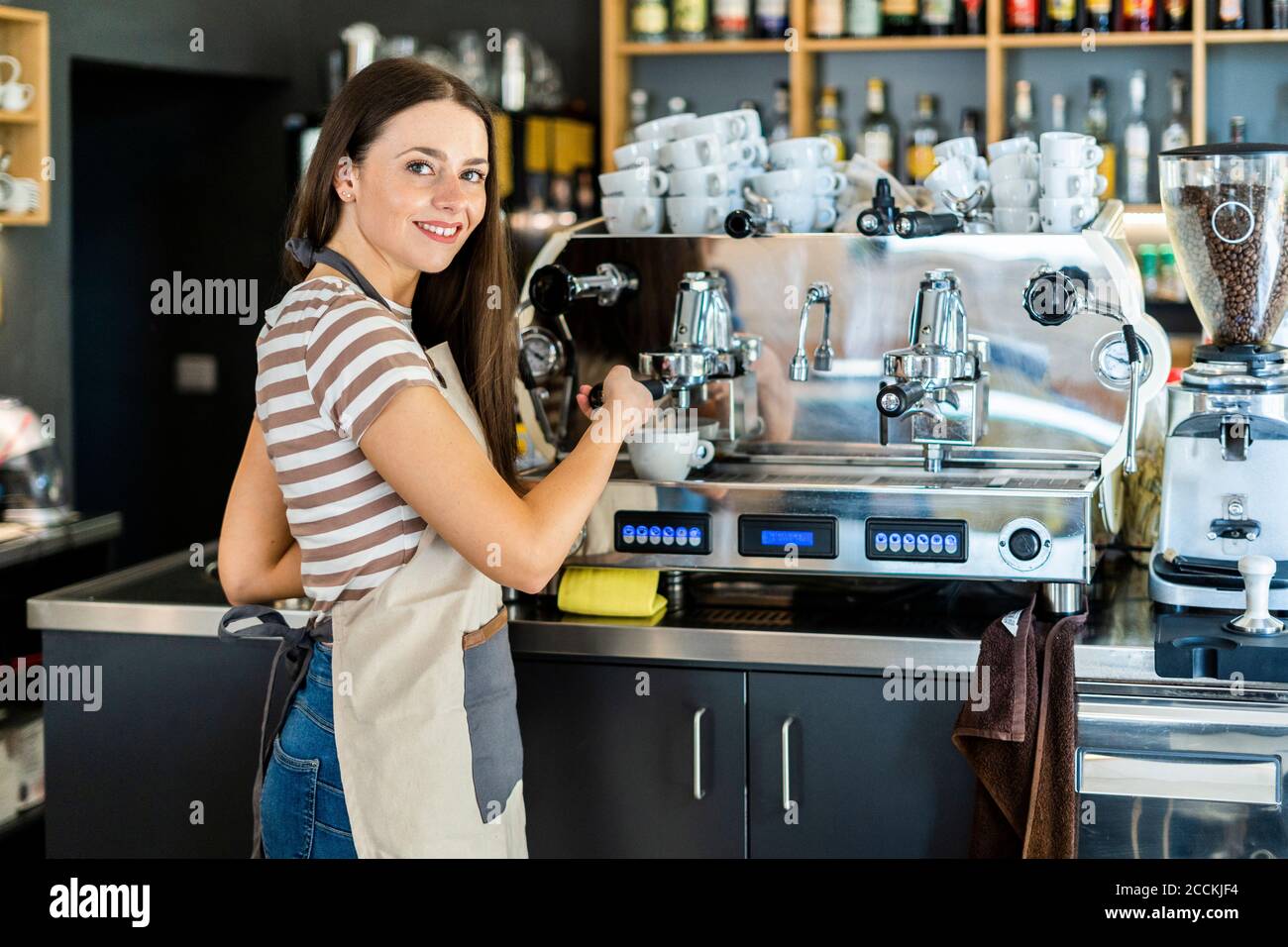 Une femme de Barista heureuse utilisant une cafetière dans un café Banque D'Images