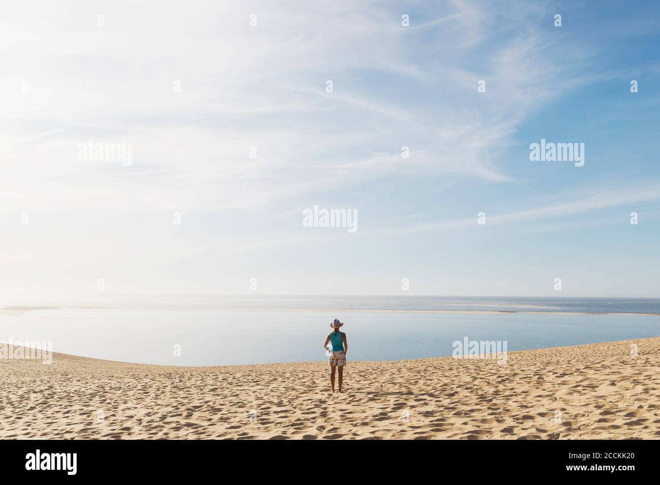 Femme regardant l'océan Atlantique en se tenant sur la plage pendant la journée ensoleillée, Dune de Pilat, Nouvelle-Aquitaine, France Banque D'Images