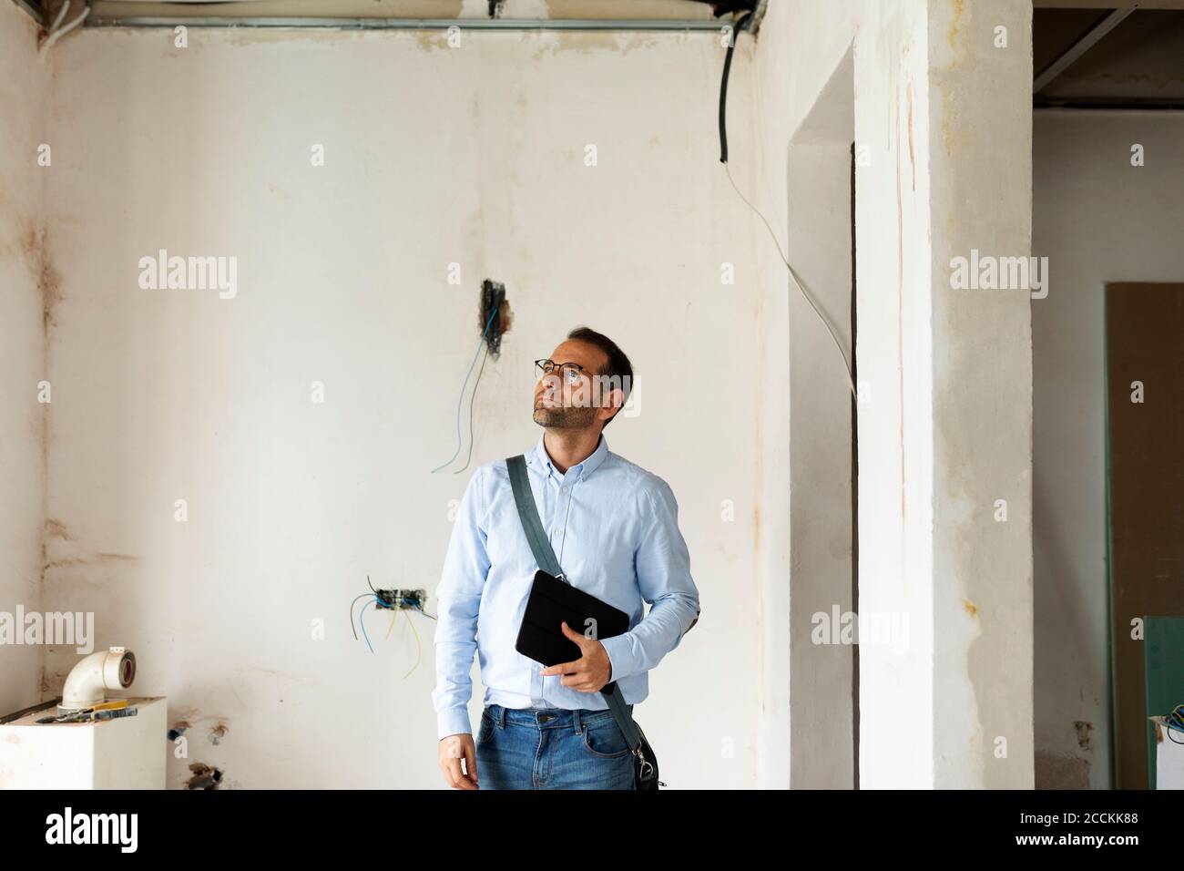 Architecte dans une maison en construction regardant autour Banque D'Images