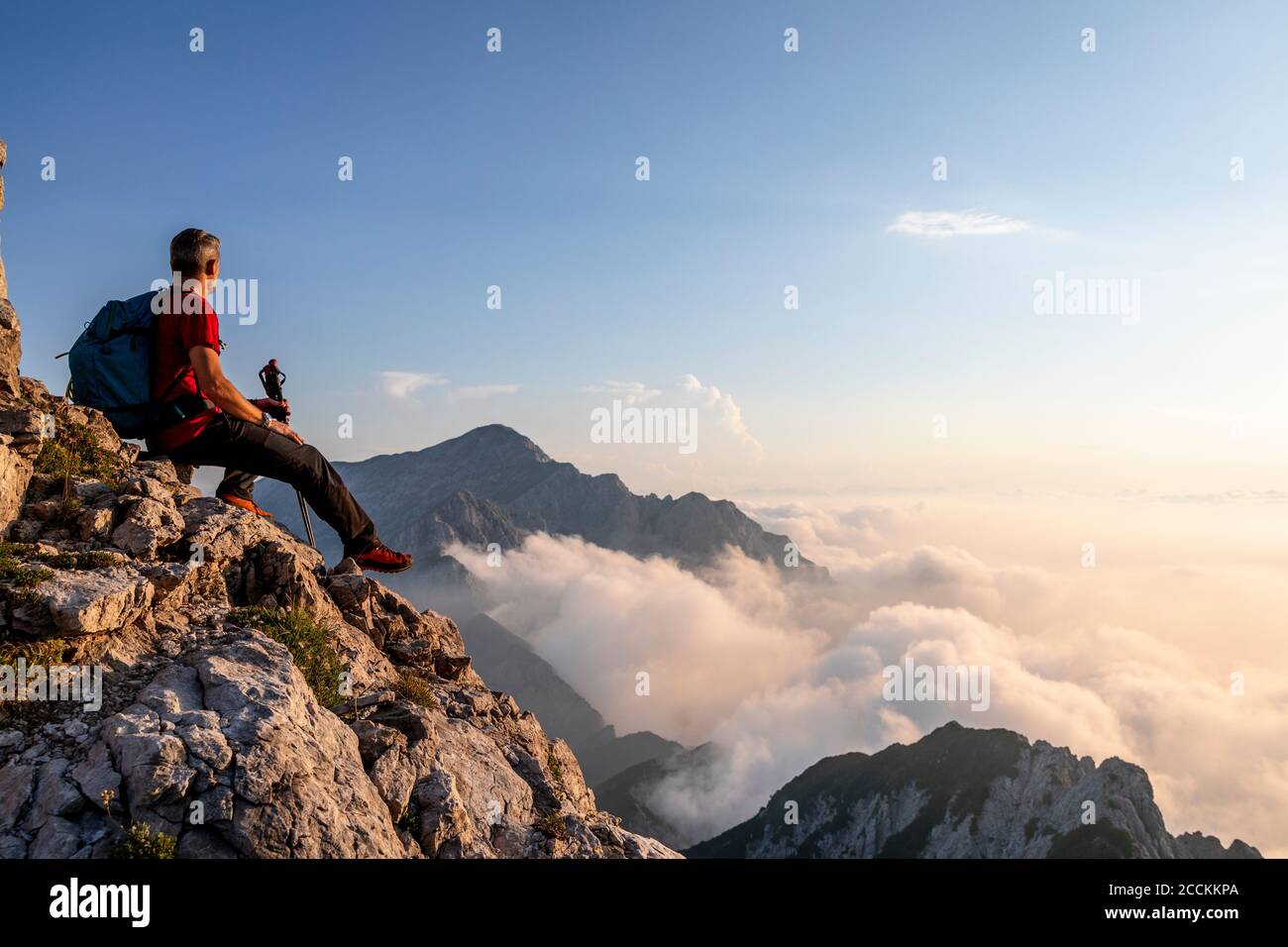 Randonneurs admirant la vue tout en étant assis au sommet du sommet de la montagne dans les Alpes de Bergame, en Italie Banque D'Images