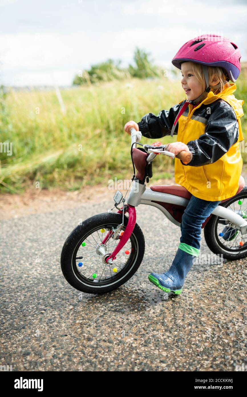 Petite fille avec casque de vélo rose sur vélo balance Banque D'Images