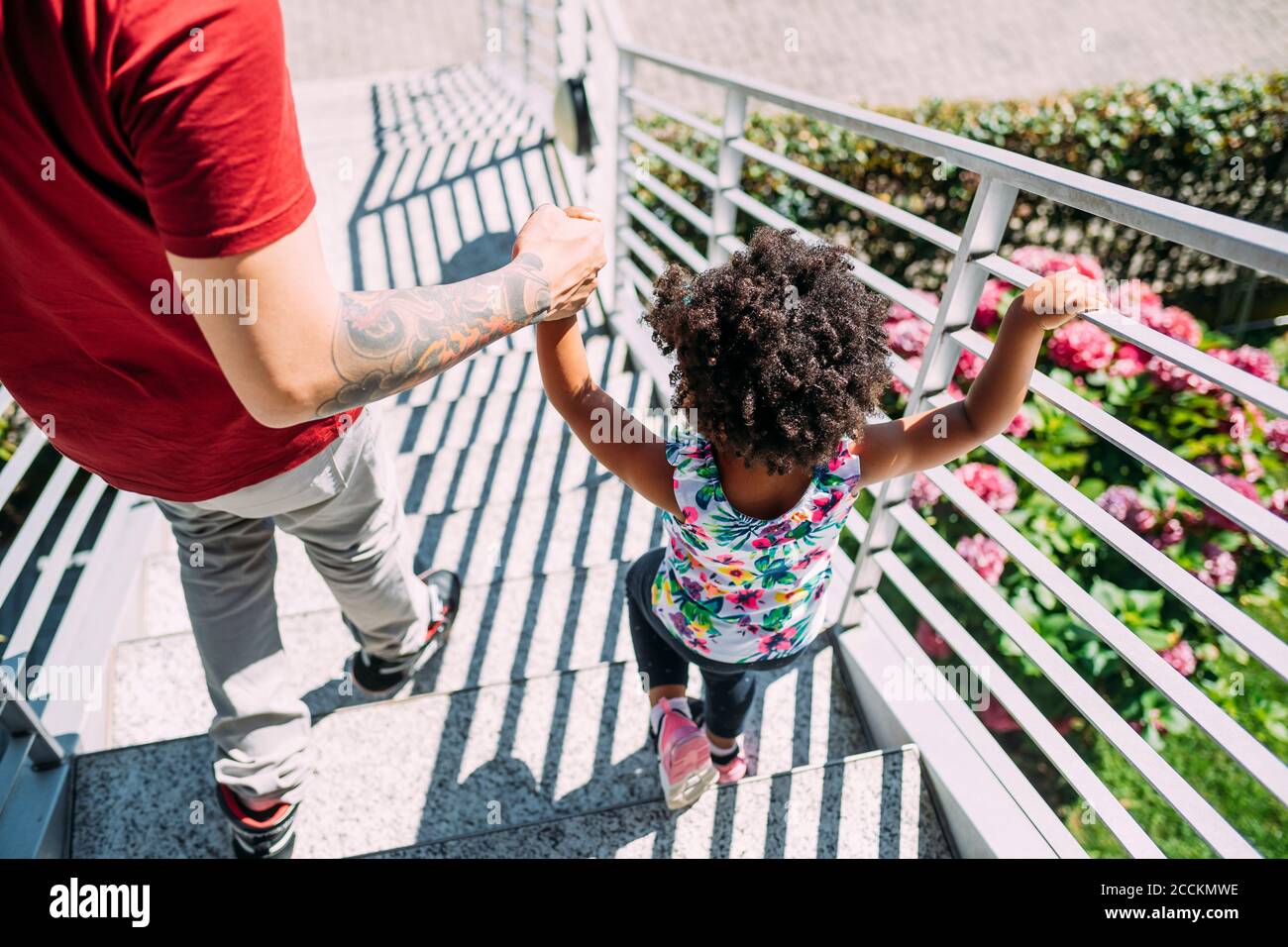 Père tenant les mains de la petite fille tout en se déplaçant sur les marches Banque D'Images